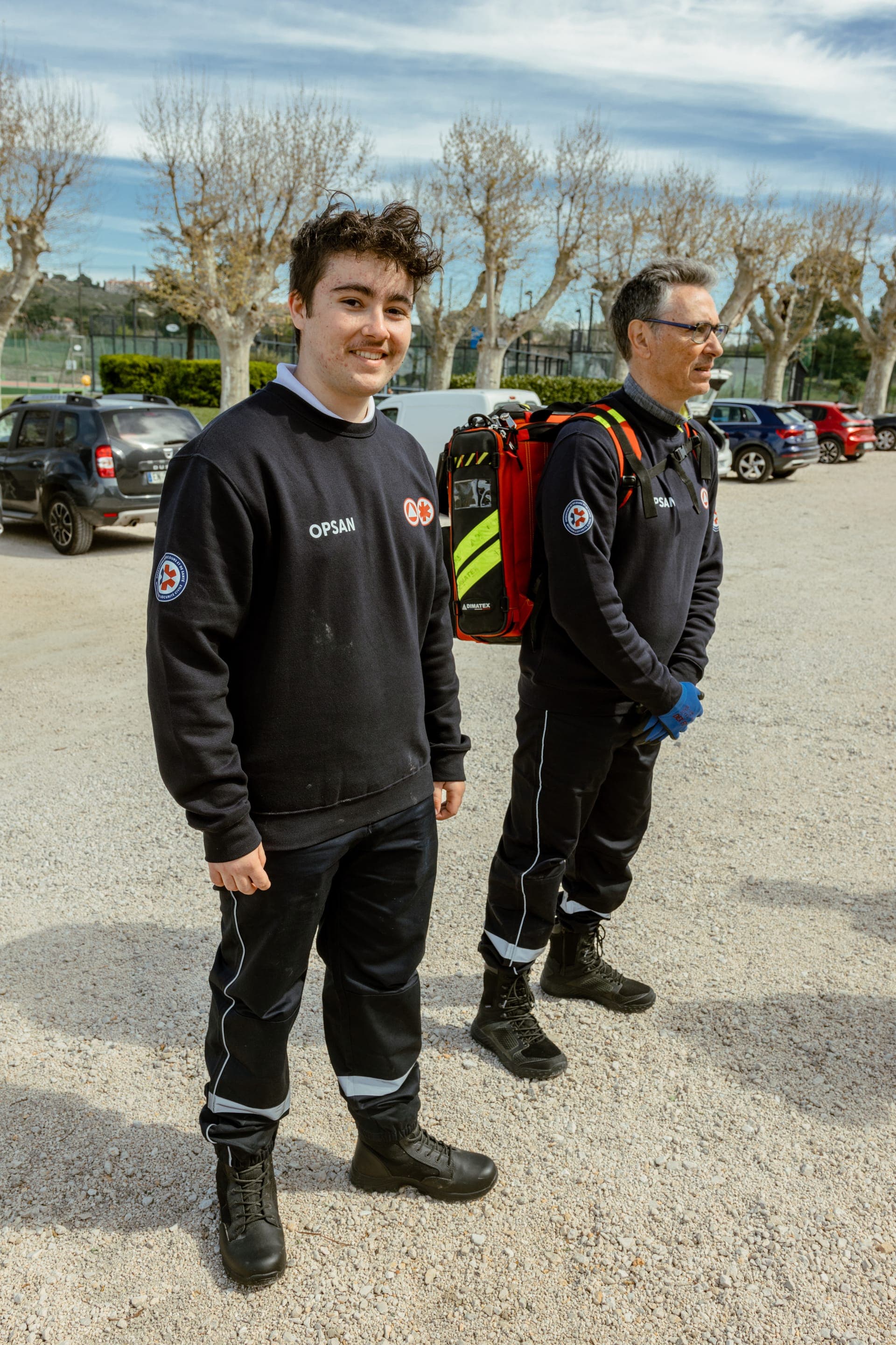Deux bénévoles OPSAN, un jeune en pull et un senior porteur du sac d'intervention